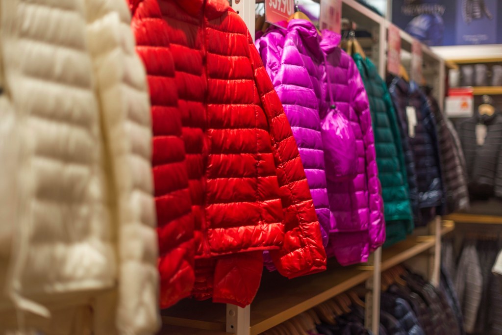 Image of brightly coloured puffer jackets on sales rack in store