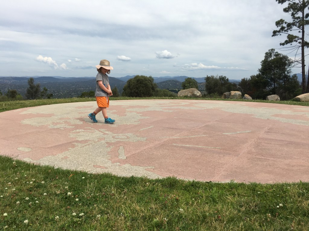 Image of young child walking across ground art of the world