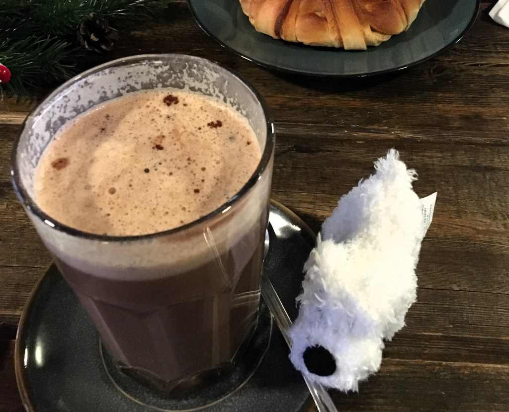 image of hot chocolate in a glass with a small soft toy white dog