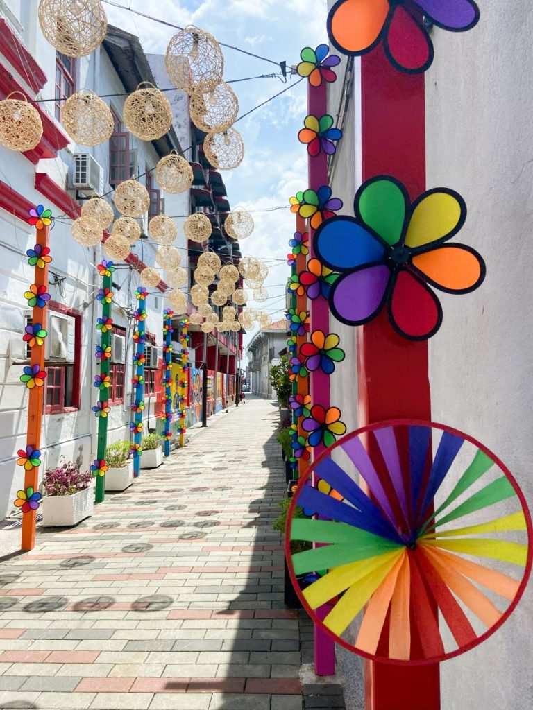 Image of art alley in George Town, Penang (Malaysia), featuring small wind-powered spinning fans in rainbow colours.