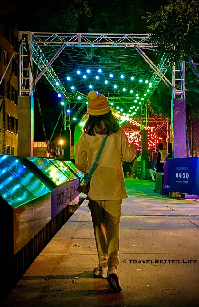 image of child walking along The Goods Line during Vivid Sydney 2024, with bright coloured lights illuminating the path in vibrant coloured archways