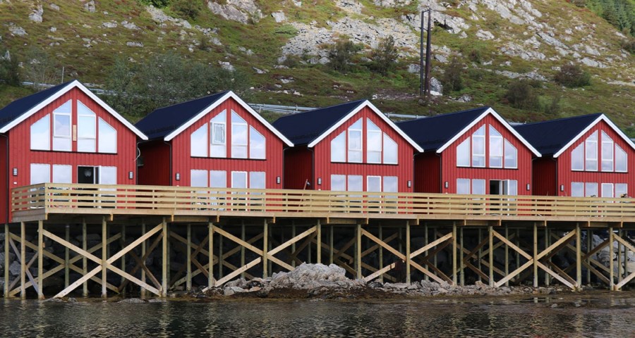 image of fishermen cabins in Lofoten Islands painted red with white trim and big windows on stilts by the coastline