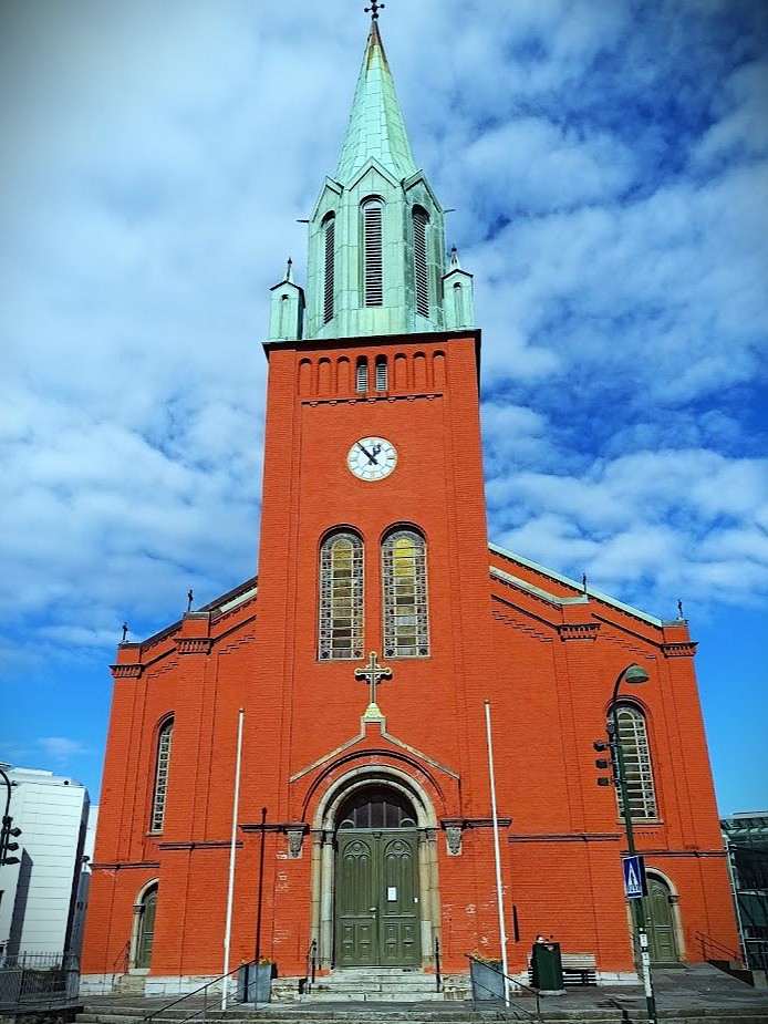 image of st petri cathedral in stavanger in Norway featuring bright red brick and a copper bell tower