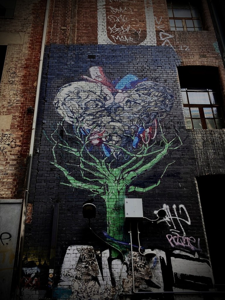 Photo of street art in Hosier Lane Melbourne that shoes a mechanical heart image as the main part of a tree stretching to the sky